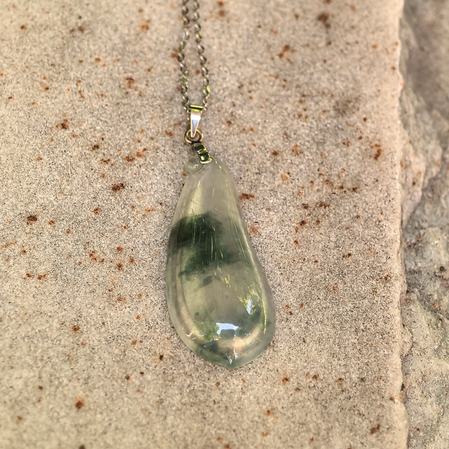 Close-up of carved melon jadeite pendant with deep green floating-flower patterns and icy translucency.
