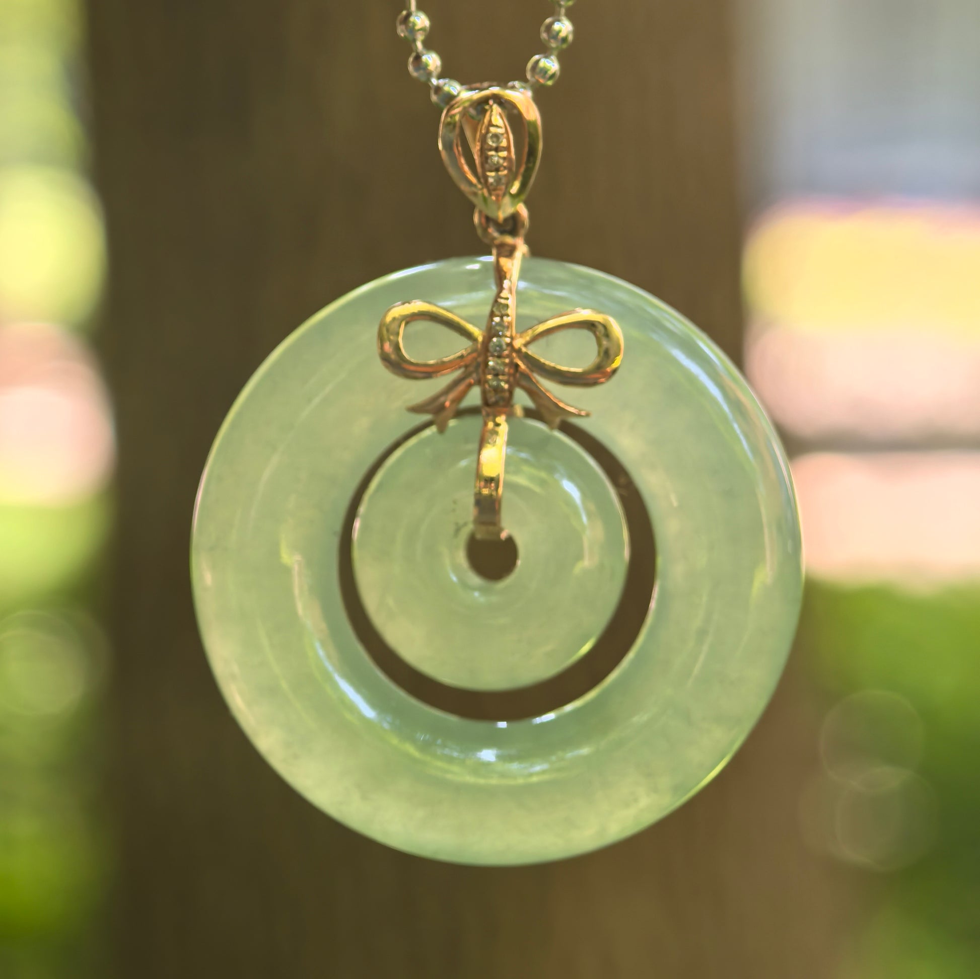 Natural Grade-A icy glutinous lake green Interlocking Donut Pendant with 18K gold bow setting.
