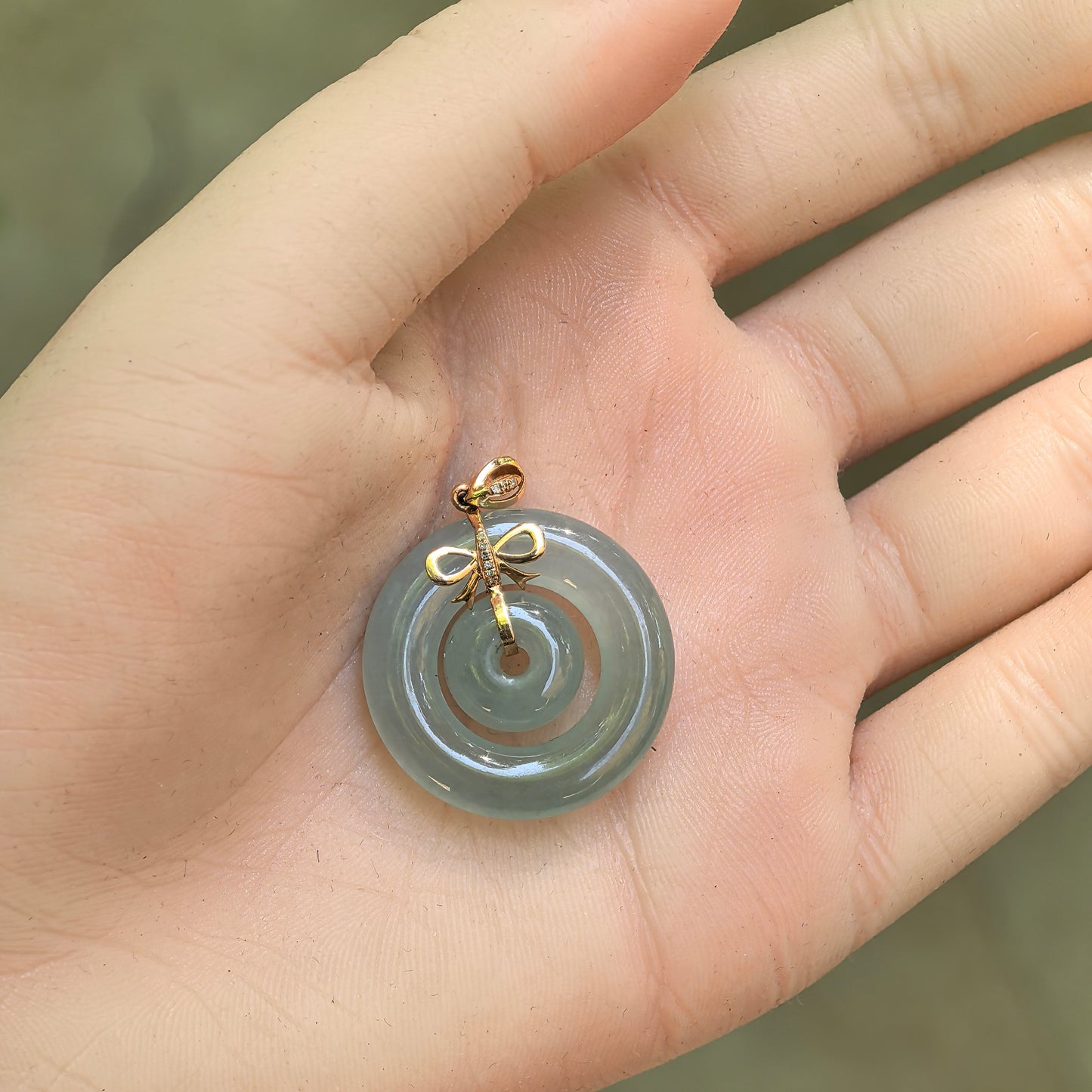 Lake green jadeite Interlocking Donut Pendant shown on hand with glossy translucent finish.

