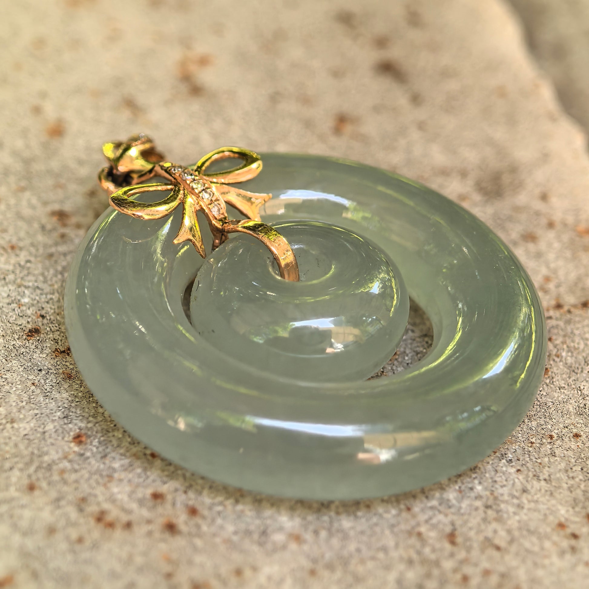 Close-up of natural Burmese jade Interlocking Donut Pendant with 18K gold and diamond accents.
