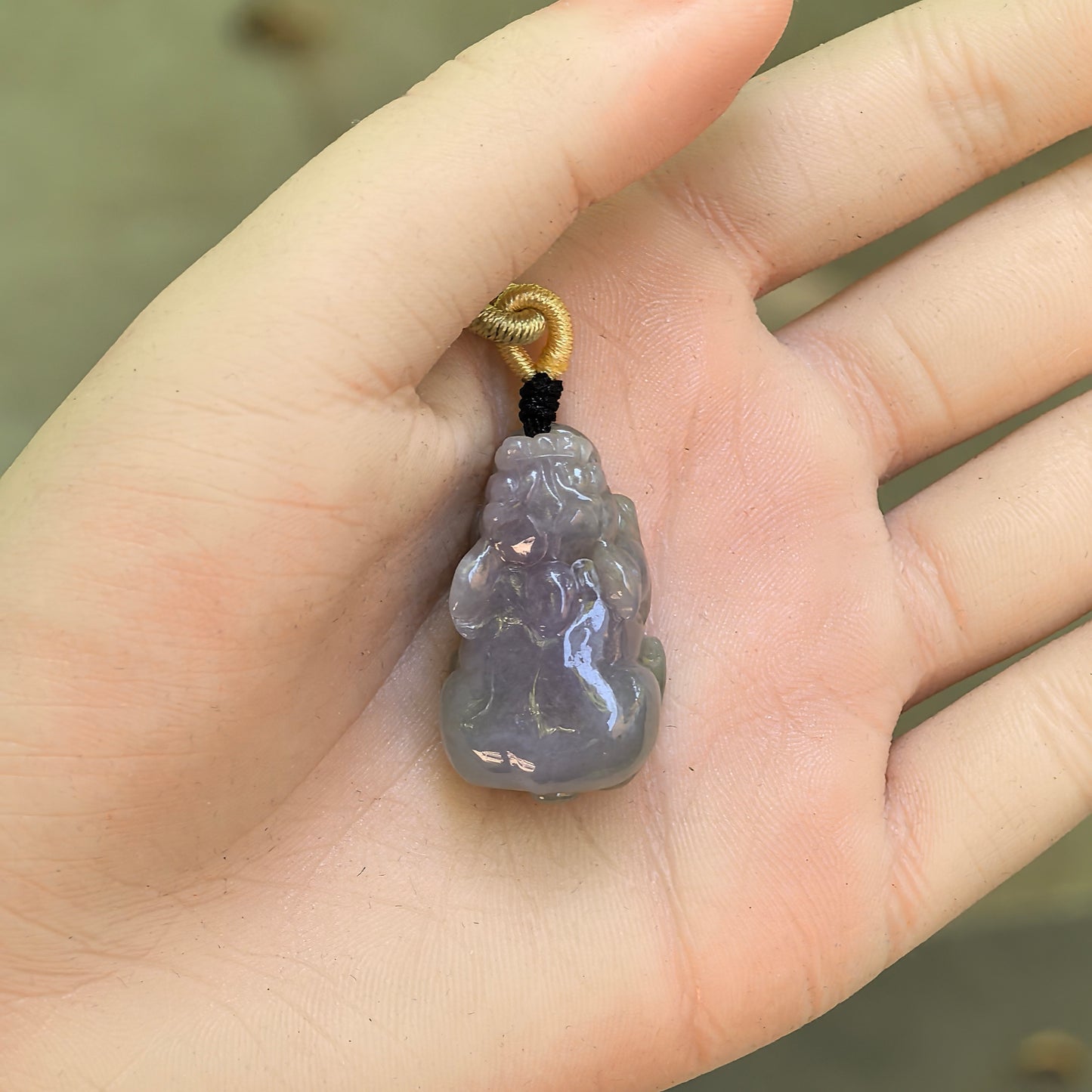 Natural Grade-A glutinous lavender purple Pixiu jadeite pendant shown on hand with cord.
