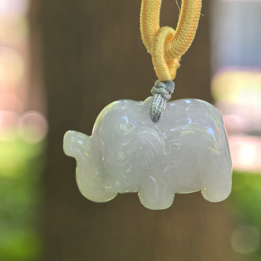 Natural Grade-A glutinous white elephant jadeite pendant hanging on yellow and blue cord.
