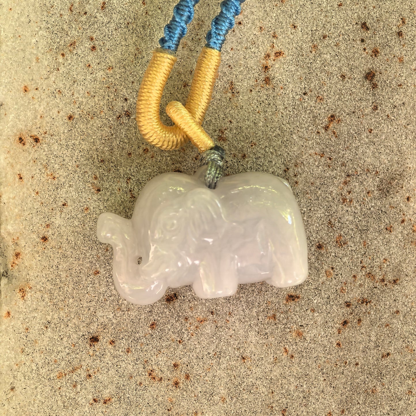 Close-up of glutinous white elephant jadeite pendant showing carved trunk, ears, and soft luster.
