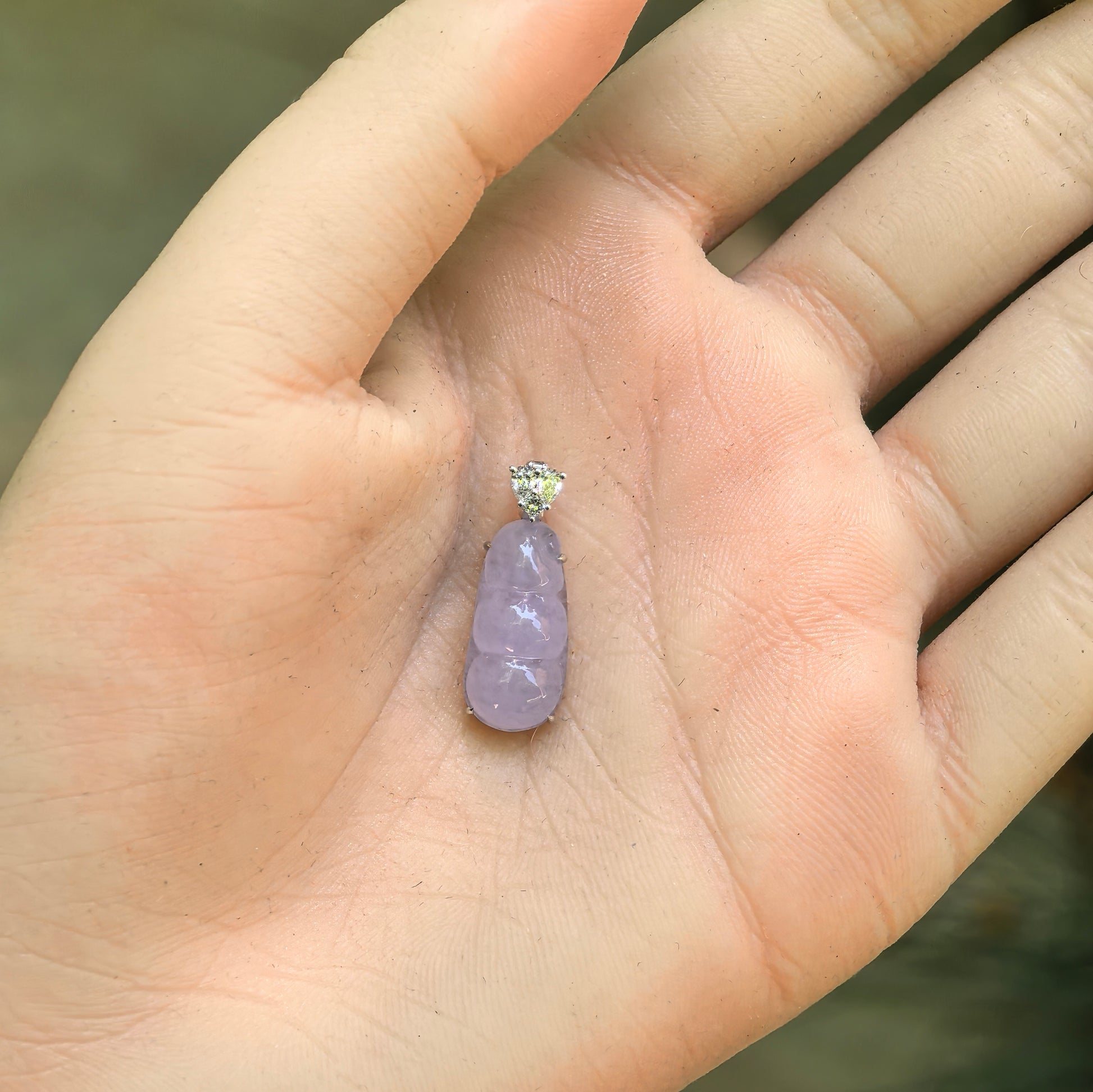 Natural Grade-A icy glutinous light lavender bean pod jadeite pendant shown in hand.
