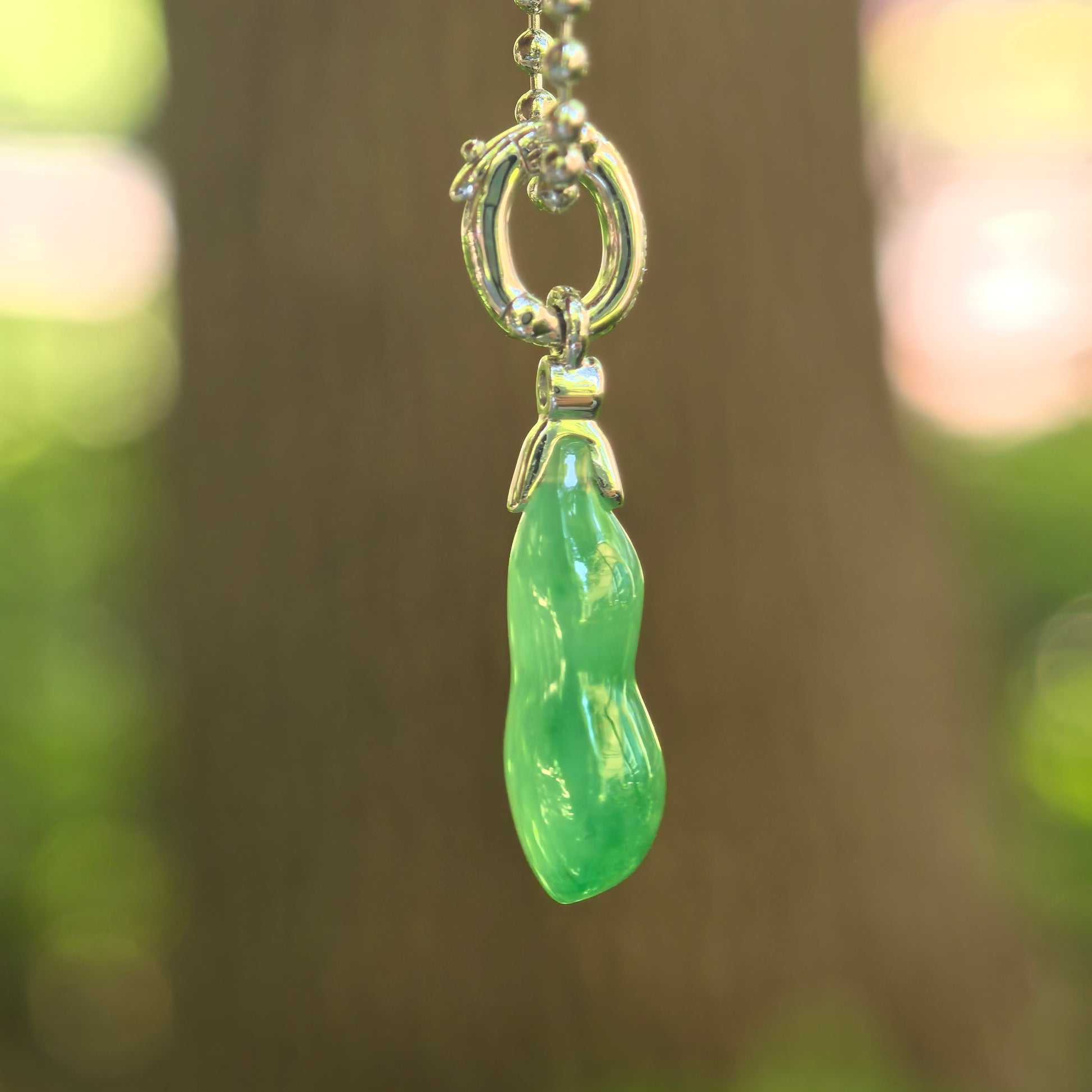 Side view of petite green gourd jadeite pendant showing icy translucency and 18K gold setting.
