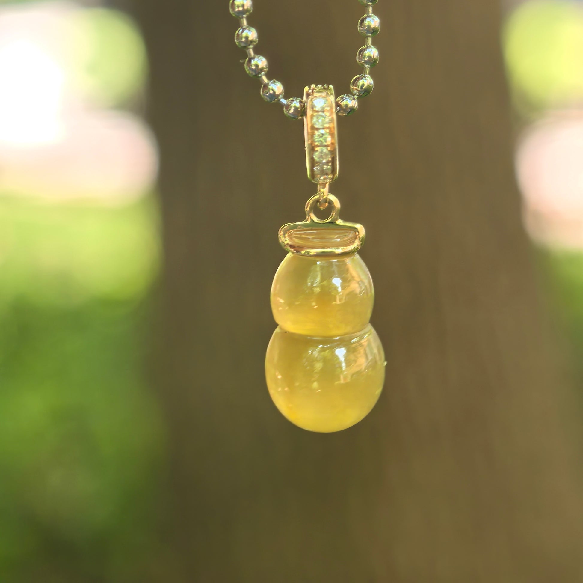 Natural Grade-A icy translucent yellow gourd jadeite pendant with 18K gold bail hanging on chain.
