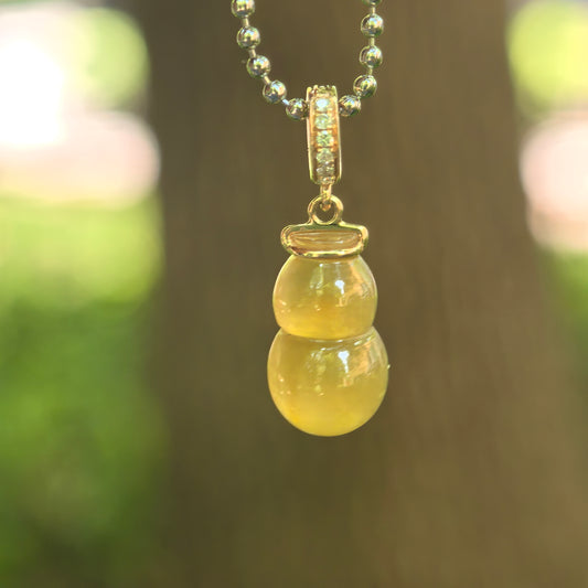 Natural Grade-A icy translucent yellow gourd jadeite pendant with 18K gold bail hanging on chain.

