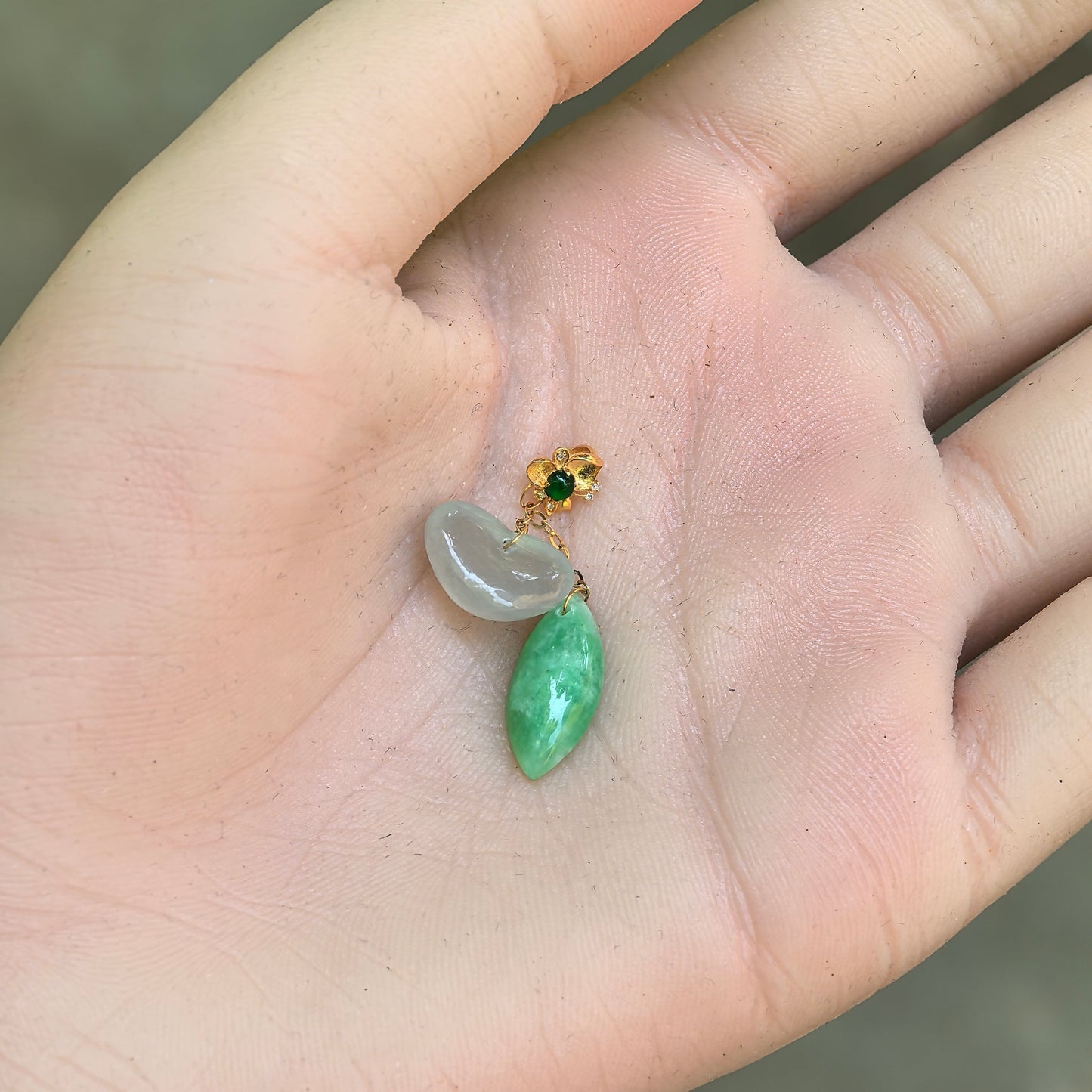 Close-up of petite white heart and green water-drop jadeite pendant shown in hand.