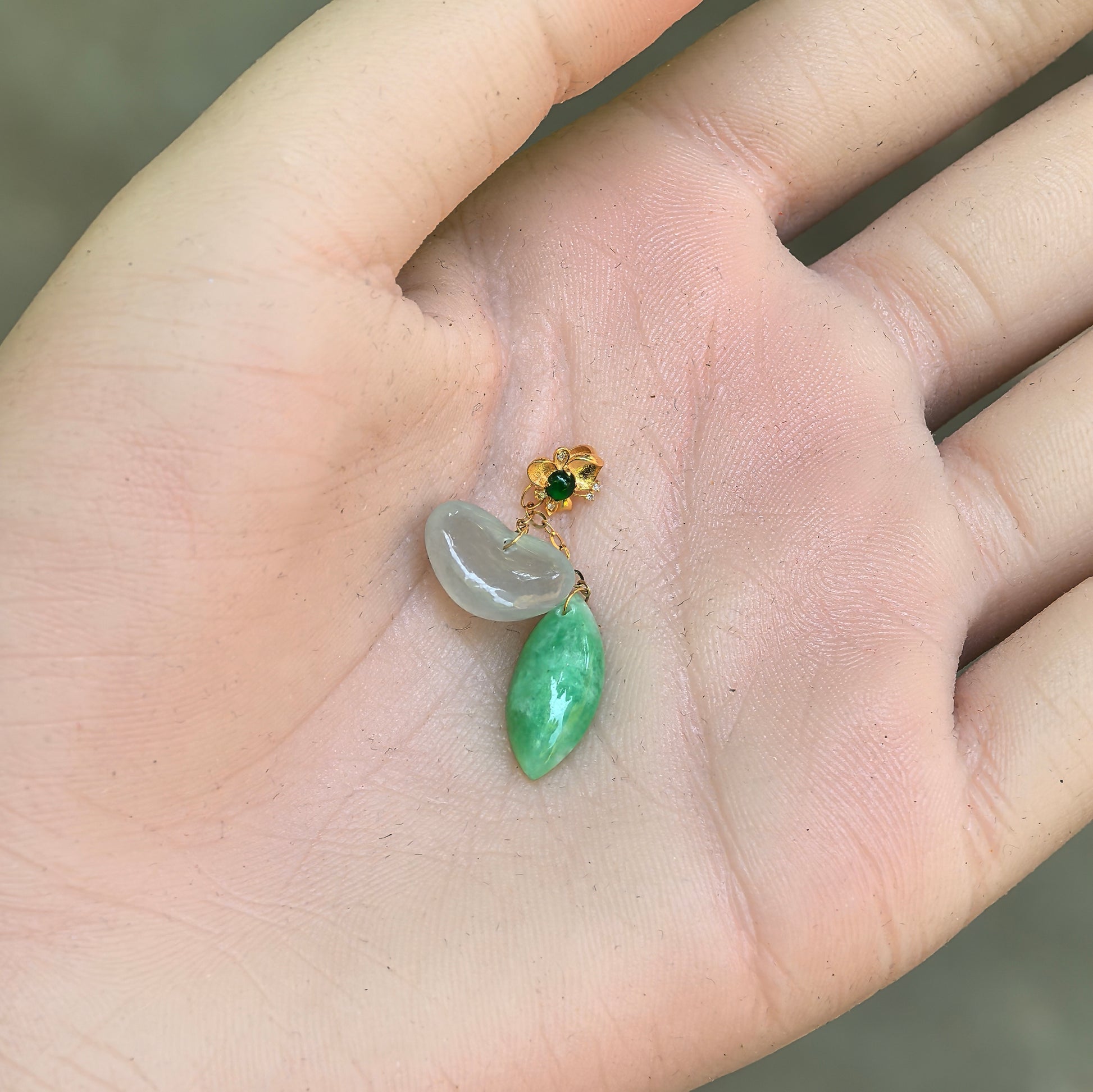 Close-up of petite white heart and green water-drop jadeite pendant shown in hand.