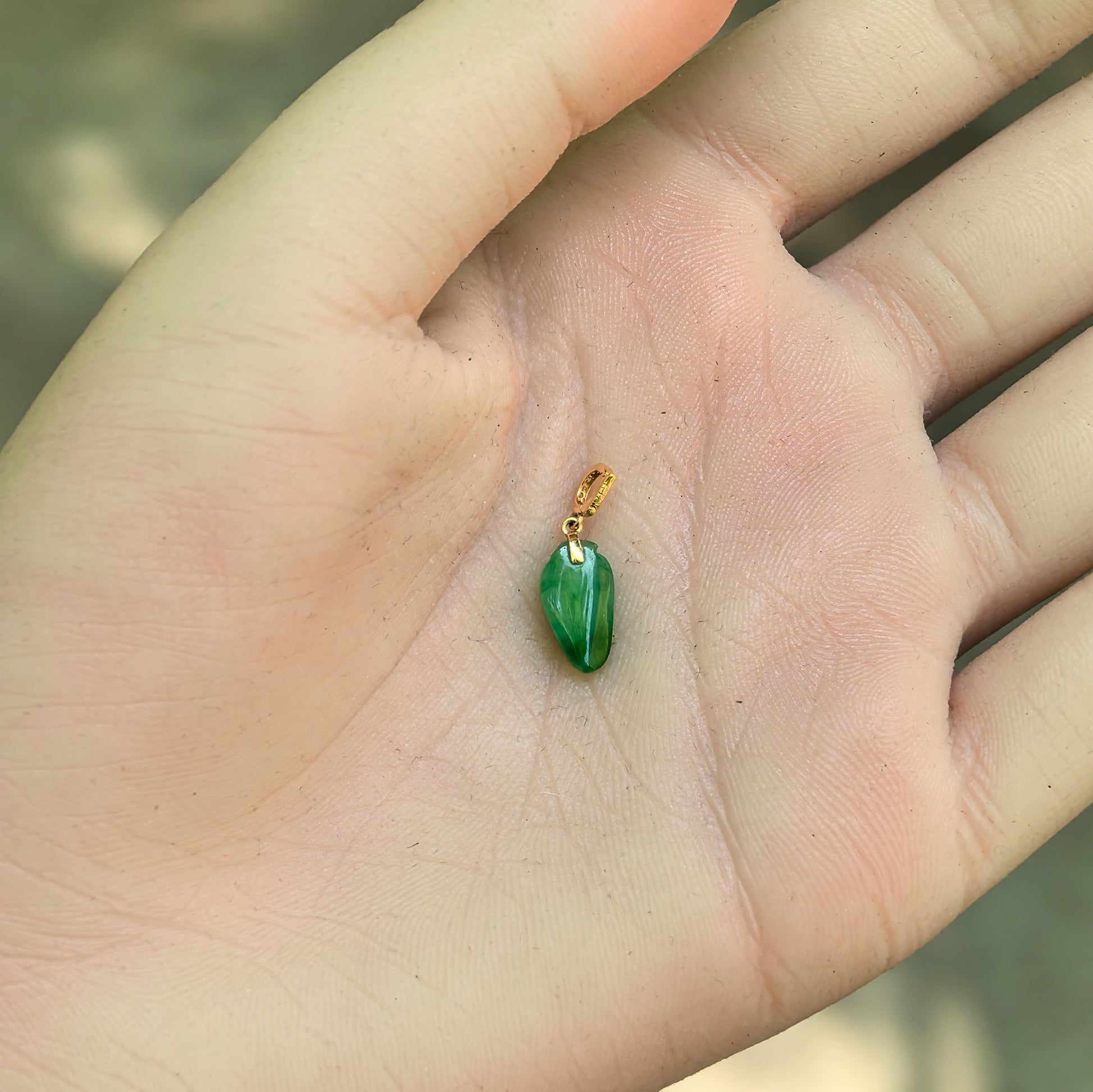 Natural Grade-A icy glutinous vivid green bamboo leaf jadeite pendant held in hand.
