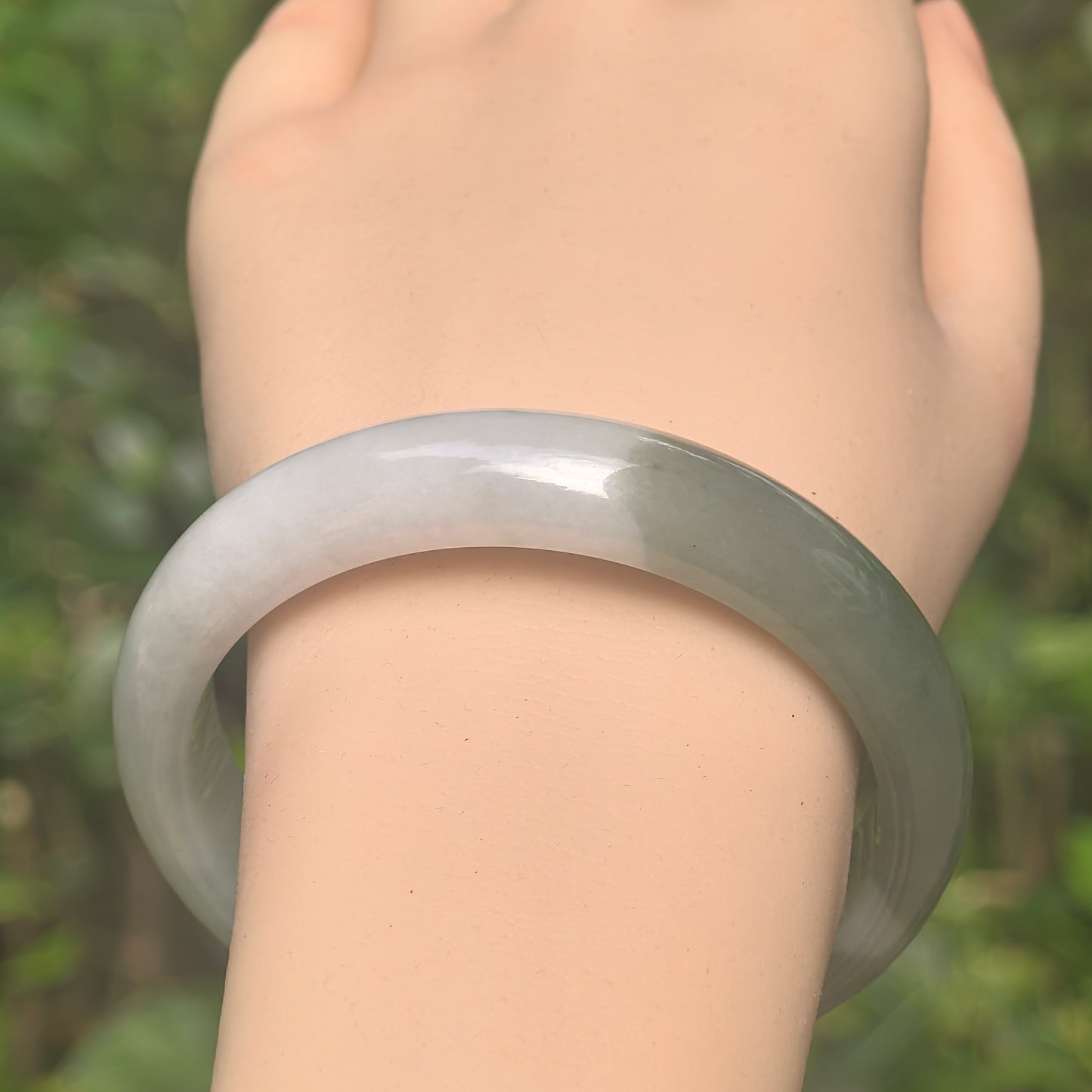 Close-up of white base and deep green jadeite bangle showing smooth polish and soft luster.
