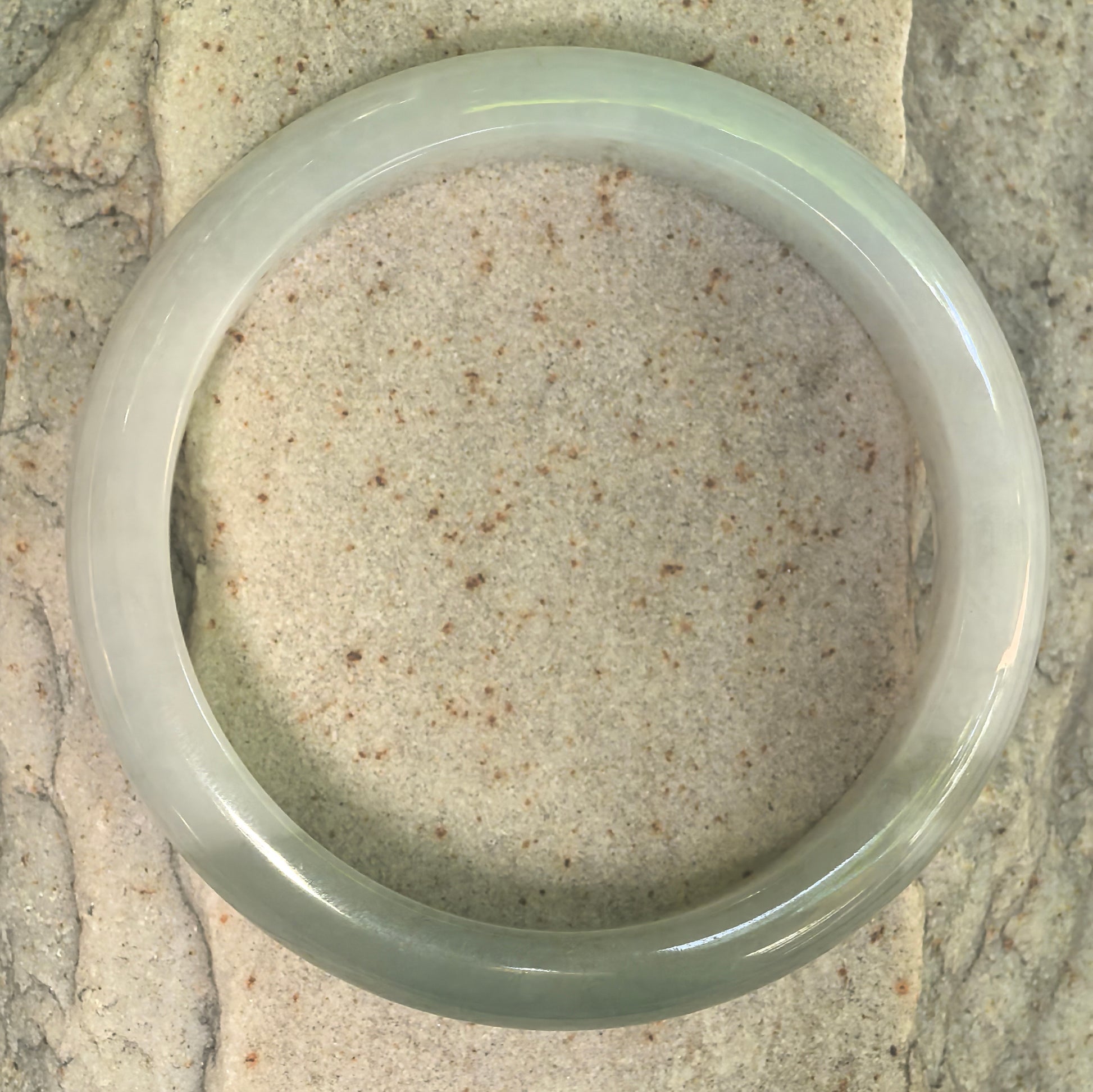 Top view of white and deep green Burmese jadeite bangle showing round bangle form.
