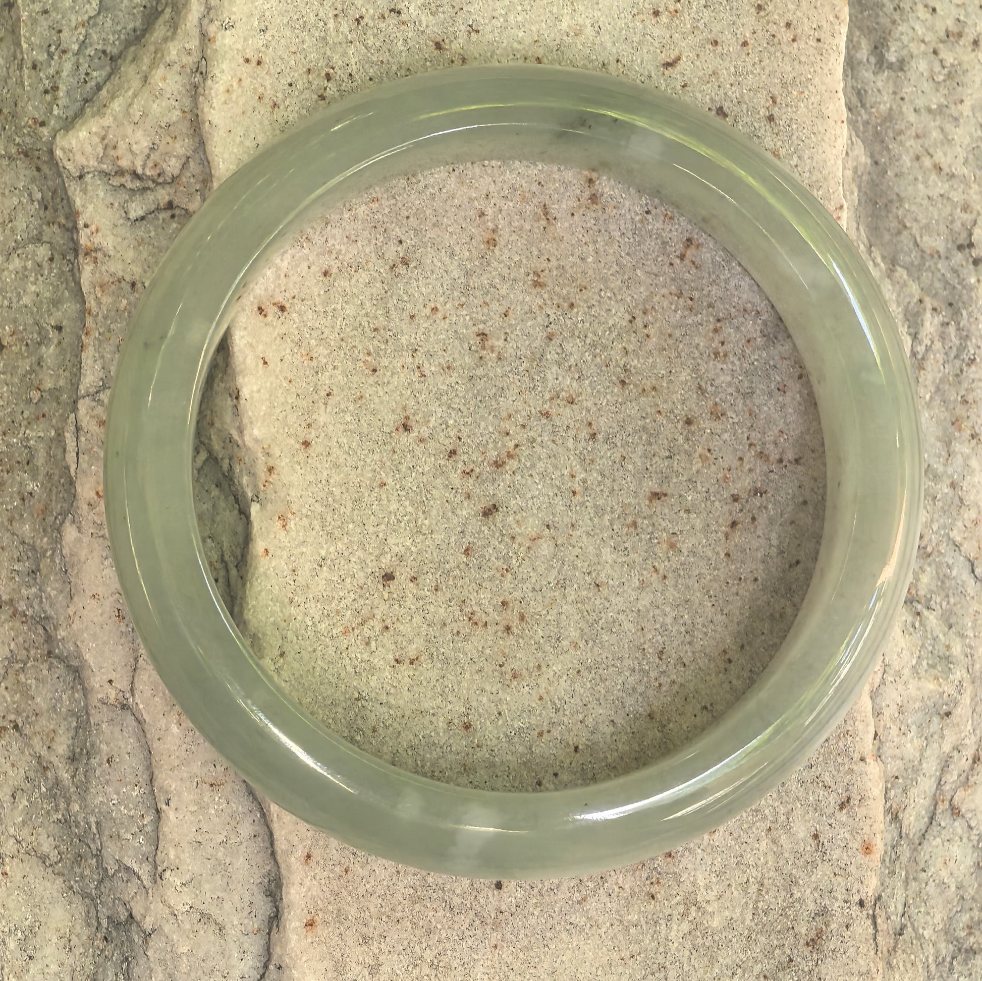 Top view of Natural Grade-A light green jadeite bangle on stone background.