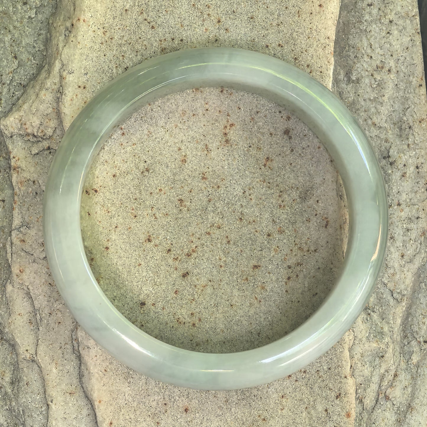 Another top view of fine glutinous light green jadeite bangle showing natural texture.
