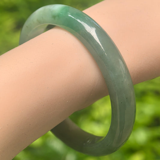 Natural Grade-A glutinous oil green jadeite D-shape bangle worn on wrist.
