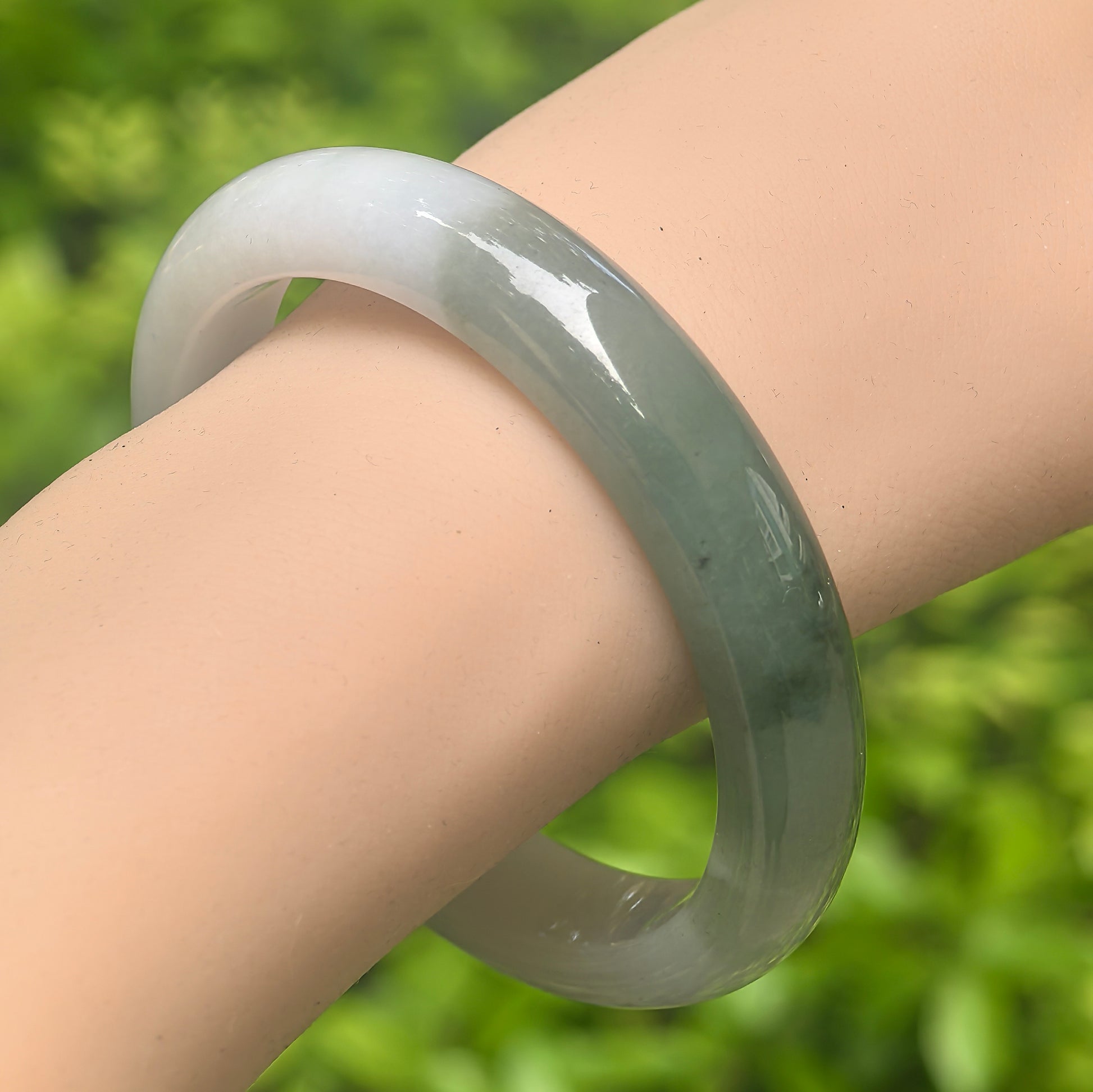 Natural Grade-A glutinous white base dark green jadeite D-shape bangle worn on wrist.

