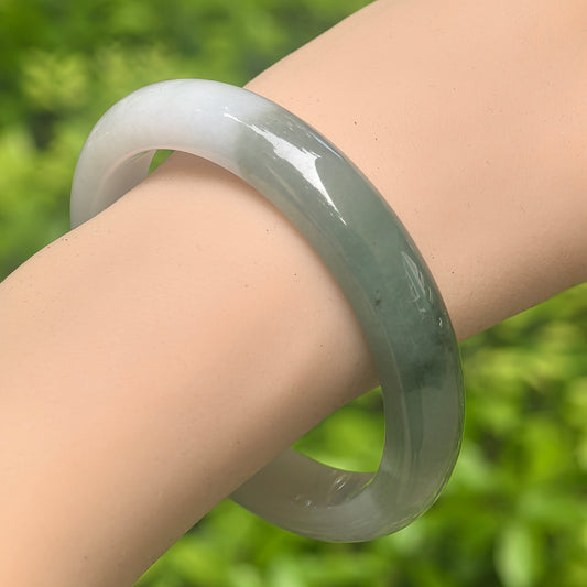 Natural Grade-A glutinous white base dark green jadeite D-shape bangle worn on wrist.
