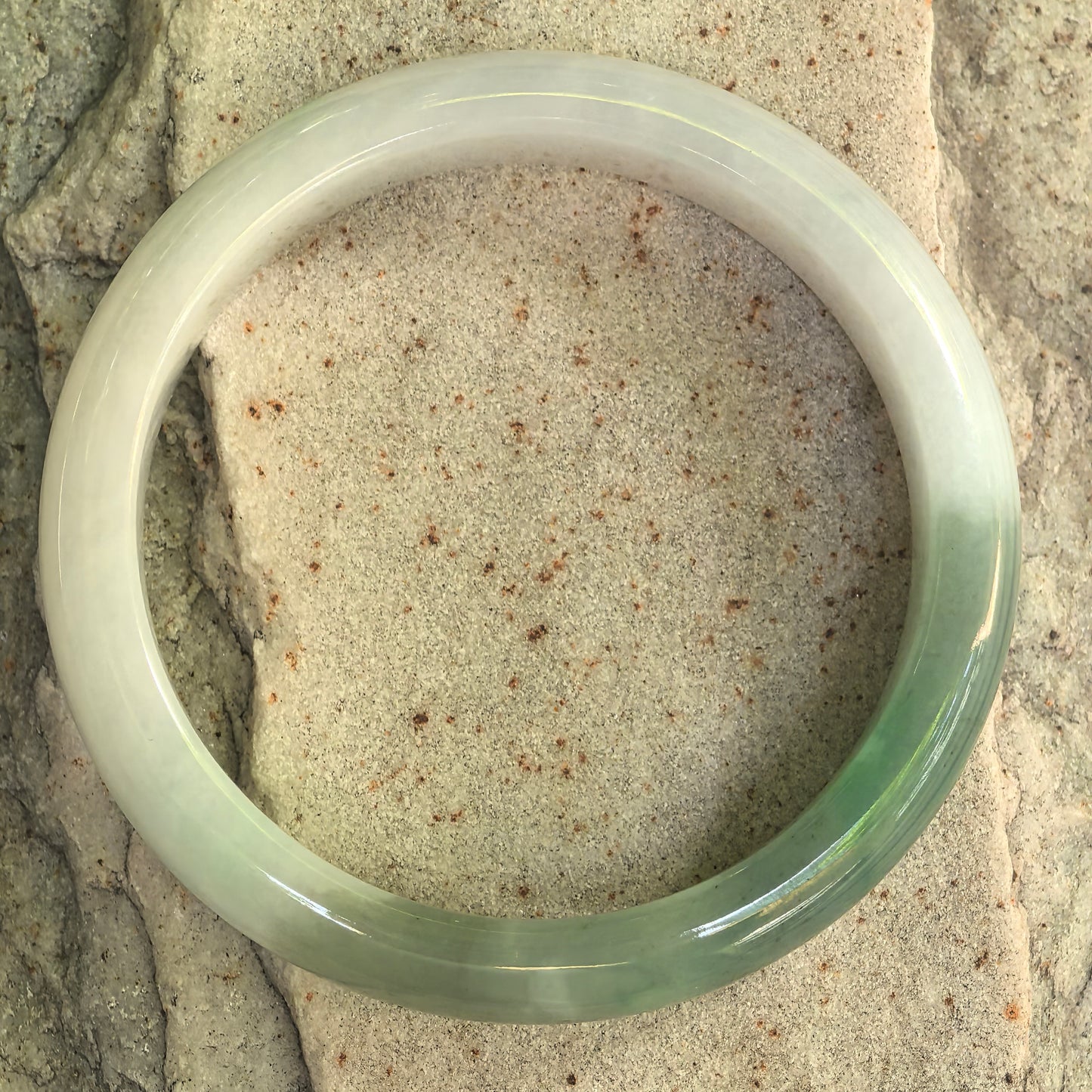Natural Grade-A white-and-green jadeite bangle displayed from the front, showing D-shape form and cotton clusters.