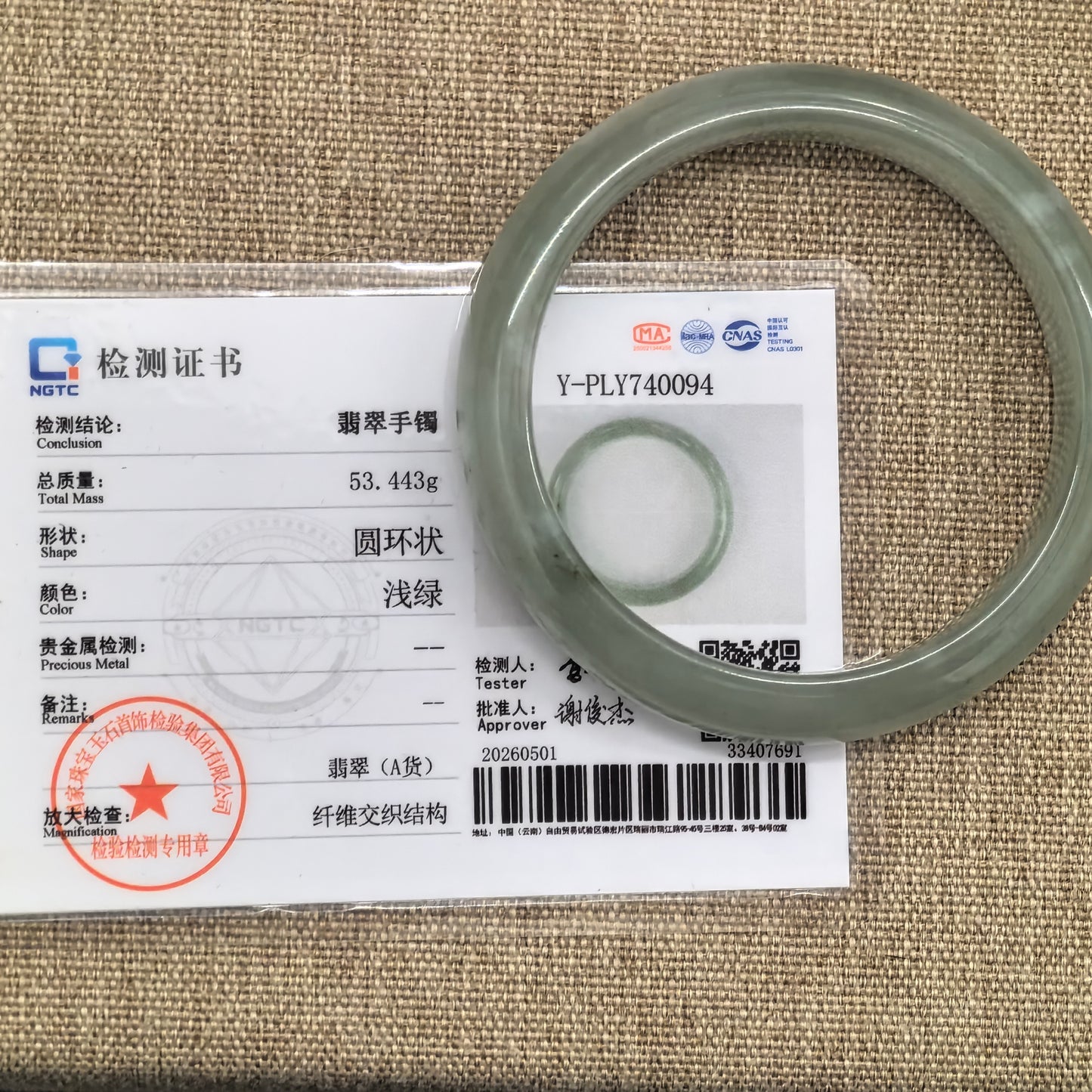 NGTC certified light green jadeite bangle displayed with matching certificate.
