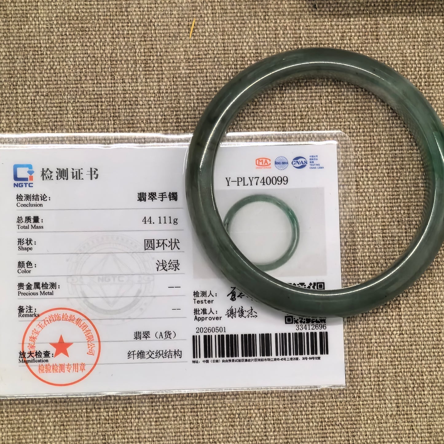 NGTC certified oil green jadeite bangle displayed with matching certificate.