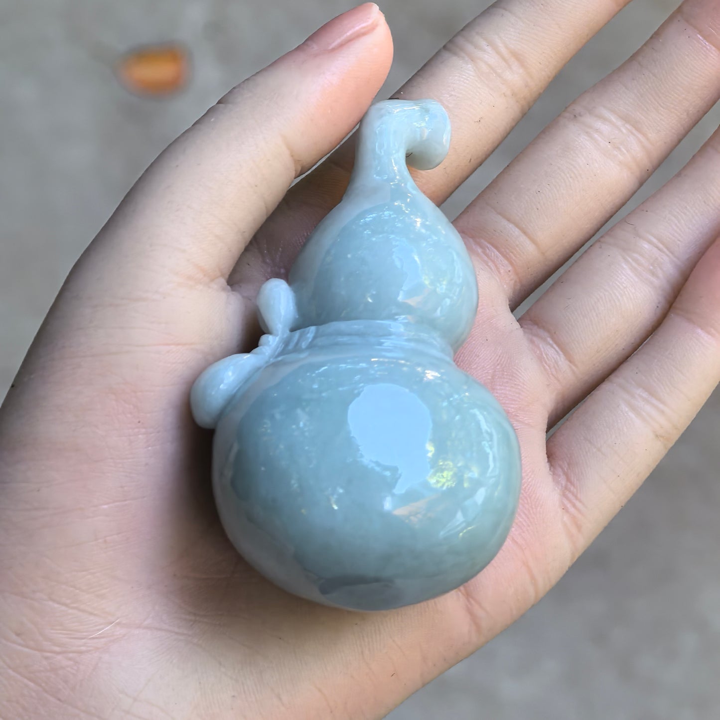 Natural Grade-A glutinous white light green gourd jadeite ornament held in hand.
