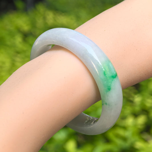 Natural Grade-A glutinous white green oval jadeite bangle worn on the wrist with fresh green accent.
