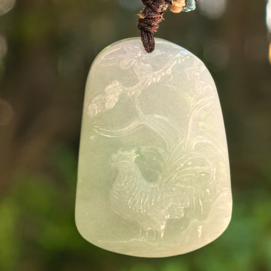 Natural Grade-A glutinous light green rooster jadeite pendant hanging on cord with floral relief carving.
