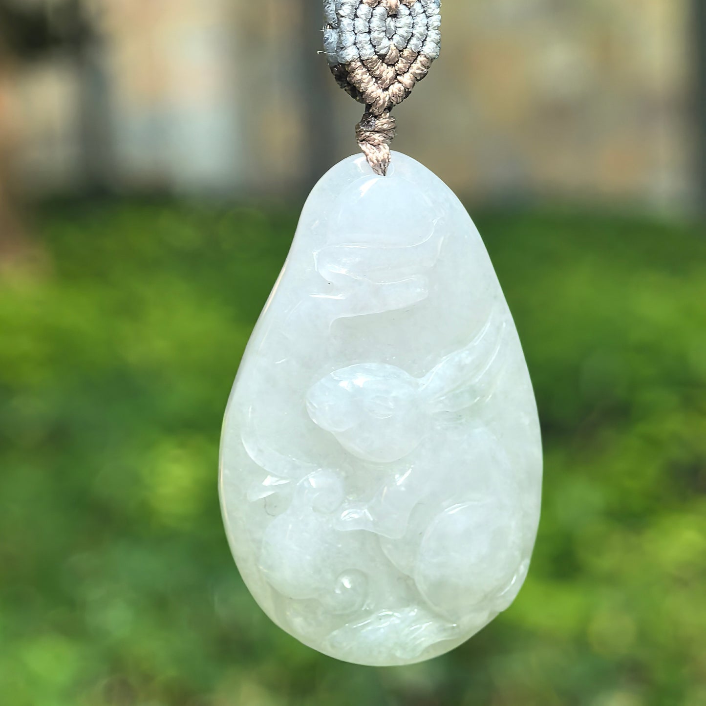 Natural Grade-A glutinous white rabbit jadeite pendant hanging on cord with soft translucent glow.
