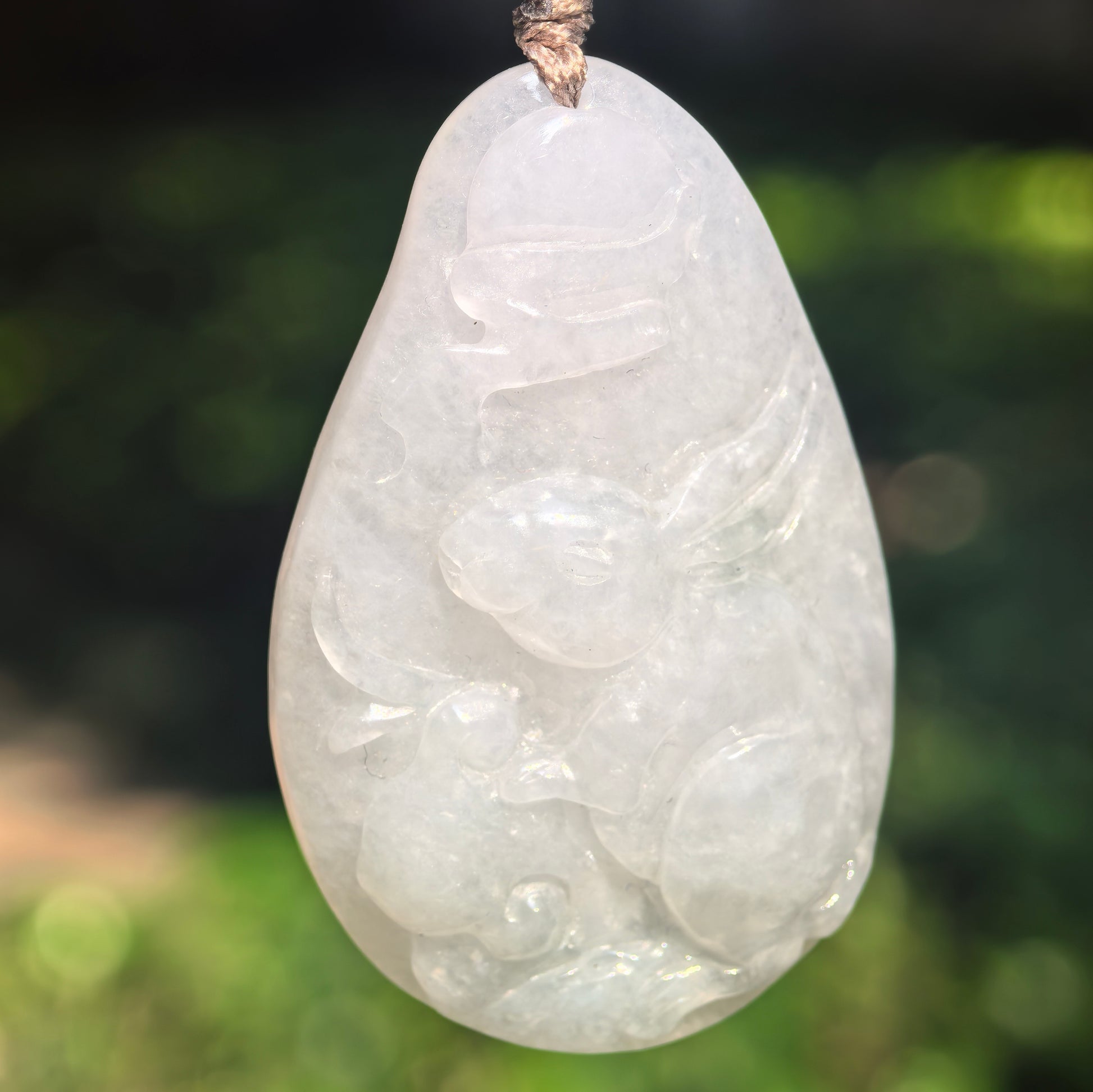 Close-up of glutinous white jadeite rabbit pendant showing smooth polish and carved details.
