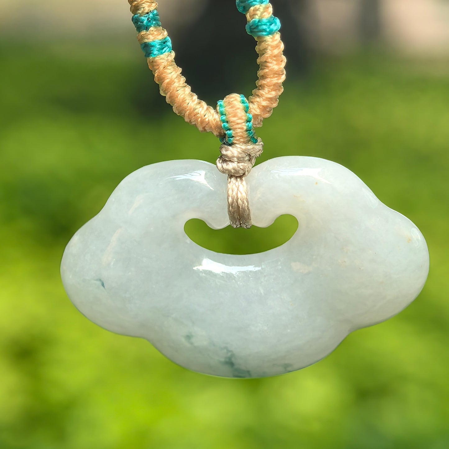 Natural Grade-A glutinous white-base auspicious cloud jadeite pendant hanging on a braided cord.