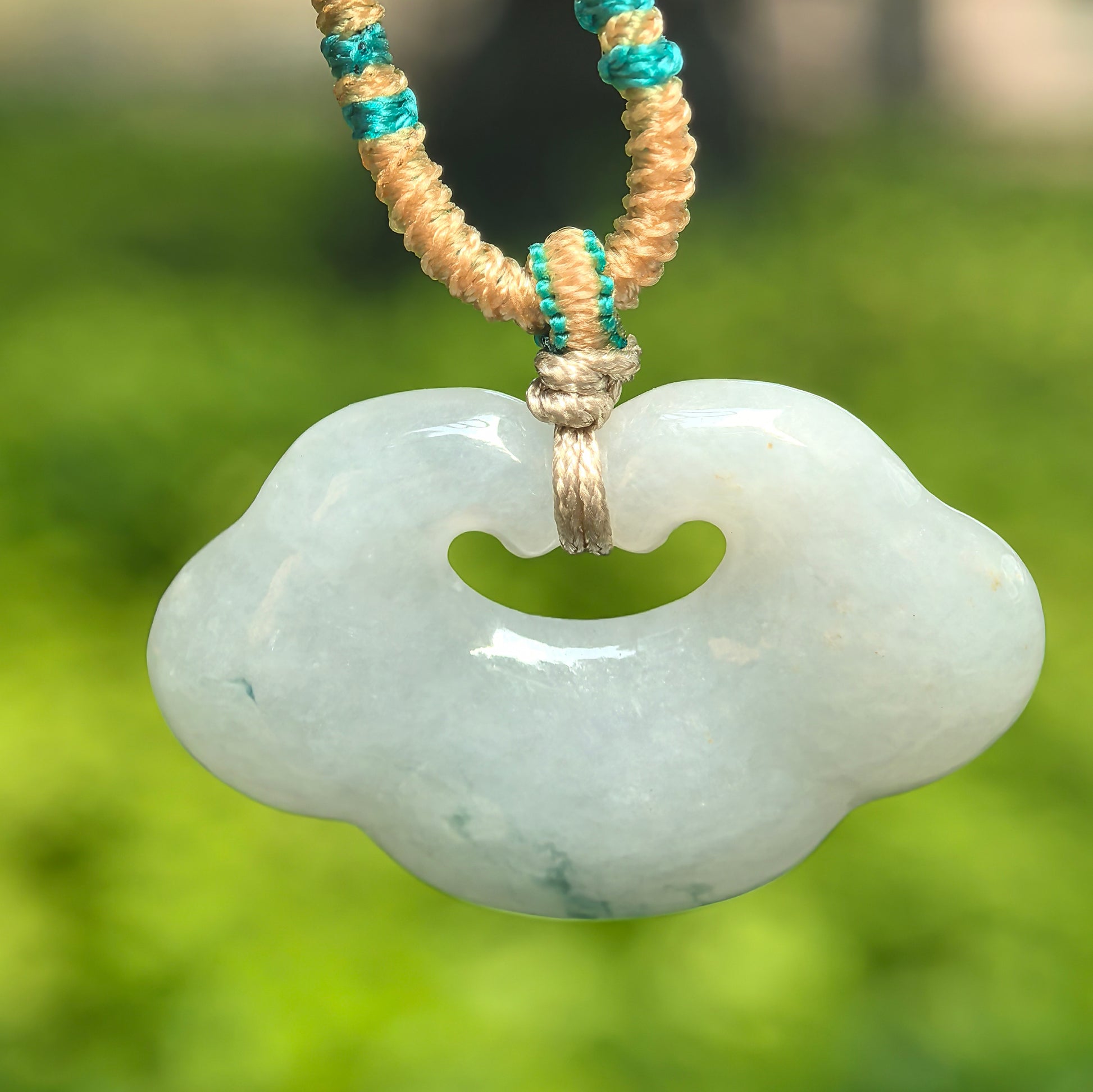 Natural Grade-A glutinous white-base auspicious cloud jadeite pendant hanging on a braided cord.