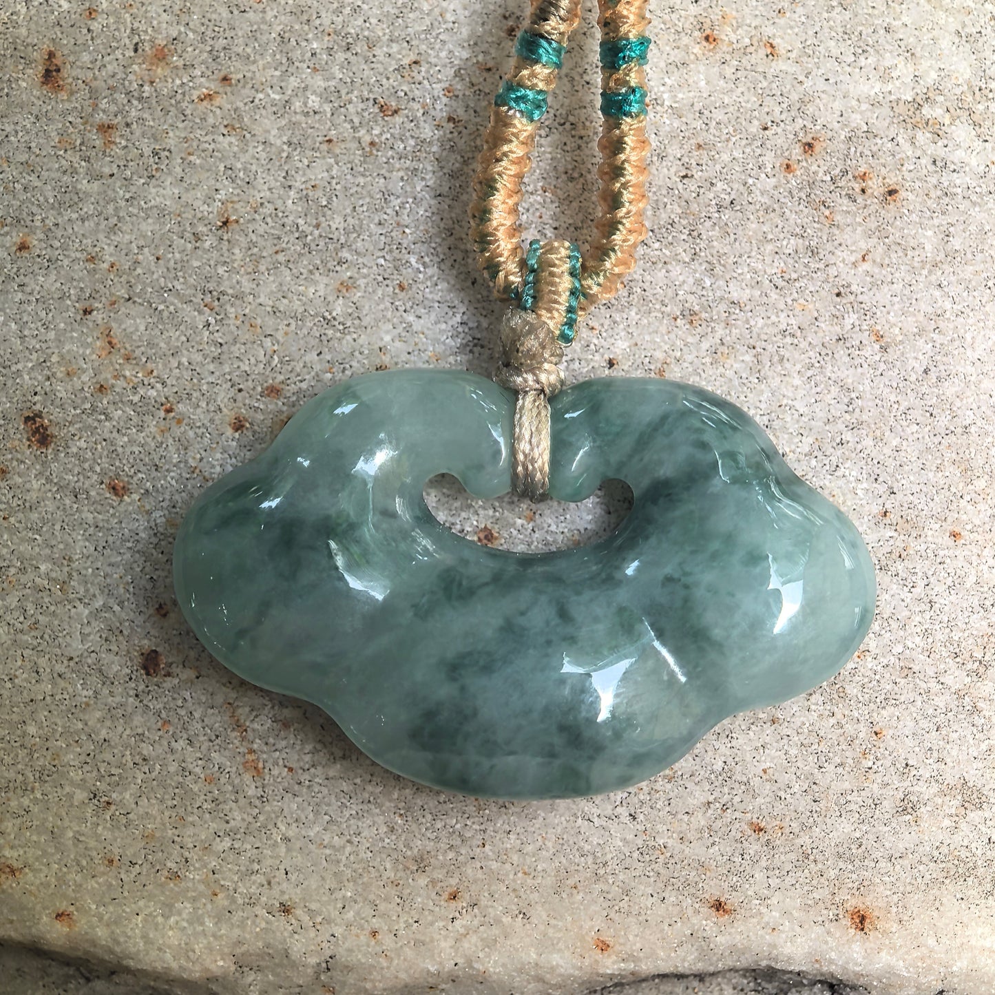 Front view of auspicious cloud jadeite pendant with floating dark green patterns.
