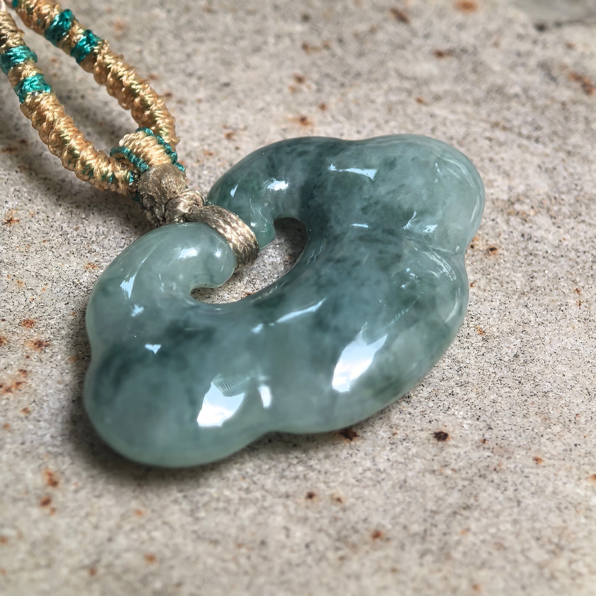Close-up of glutinous jadeite cloud pendant showing smooth polished carving.
