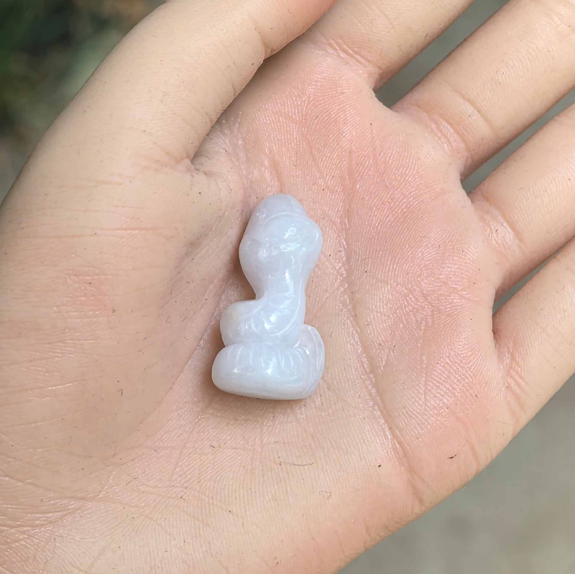 Natural Grade-A glutinous white cartoon snake jadeite ornament shown in hand with smooth milky texture.

