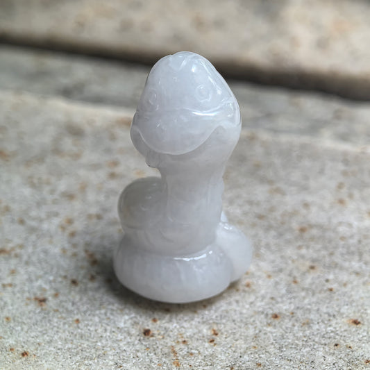 Close-up of white cartoon snake jadeite ornament showing rounded head and compact carved body.
