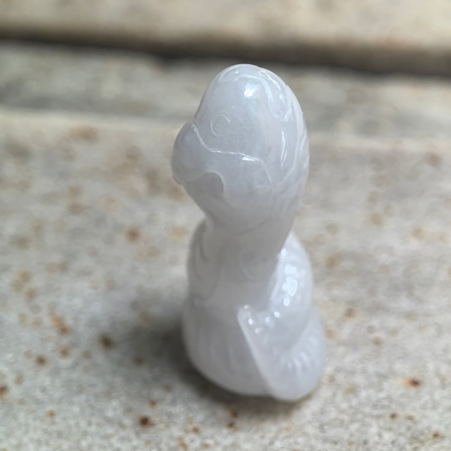 Side view of glutinous white snake jadeite ornament with polished three-dimensional carving.
