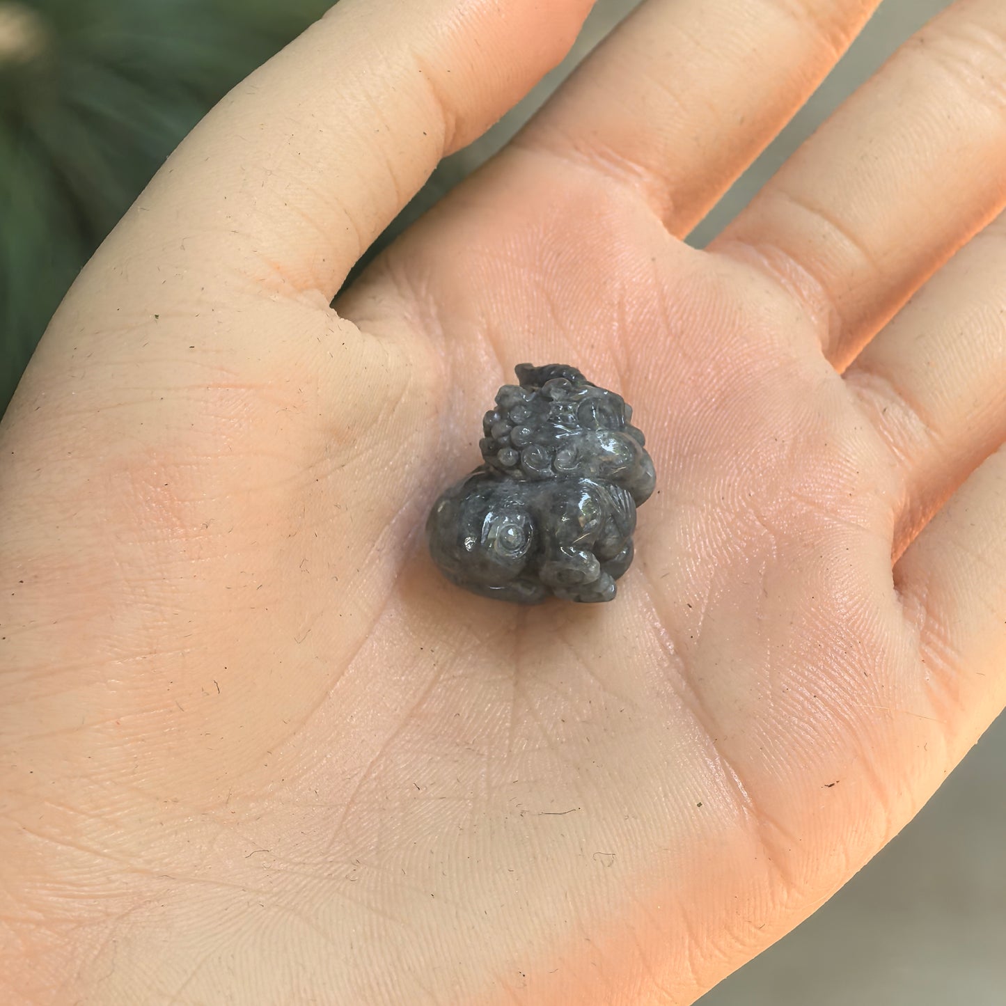 Small black-gray Pixiu jadeite ornament displayed in hand for size reference.
