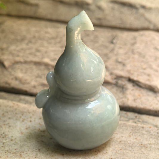 Close-up of rounded double-gourd jadeite ornament showing soft white and light green tone.
