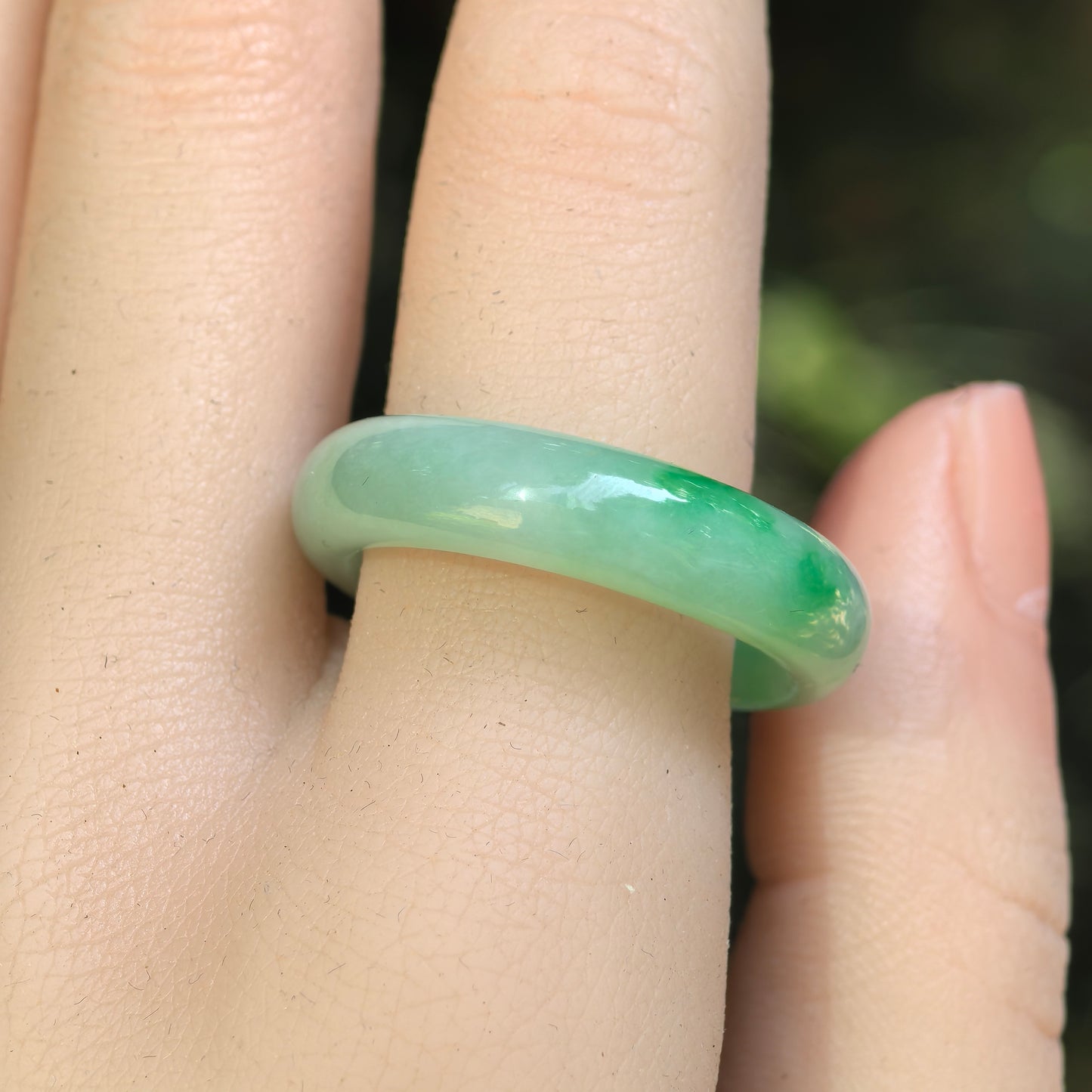 Close-up of light green jadeite ring band showing vivid green floating-flower accents.
