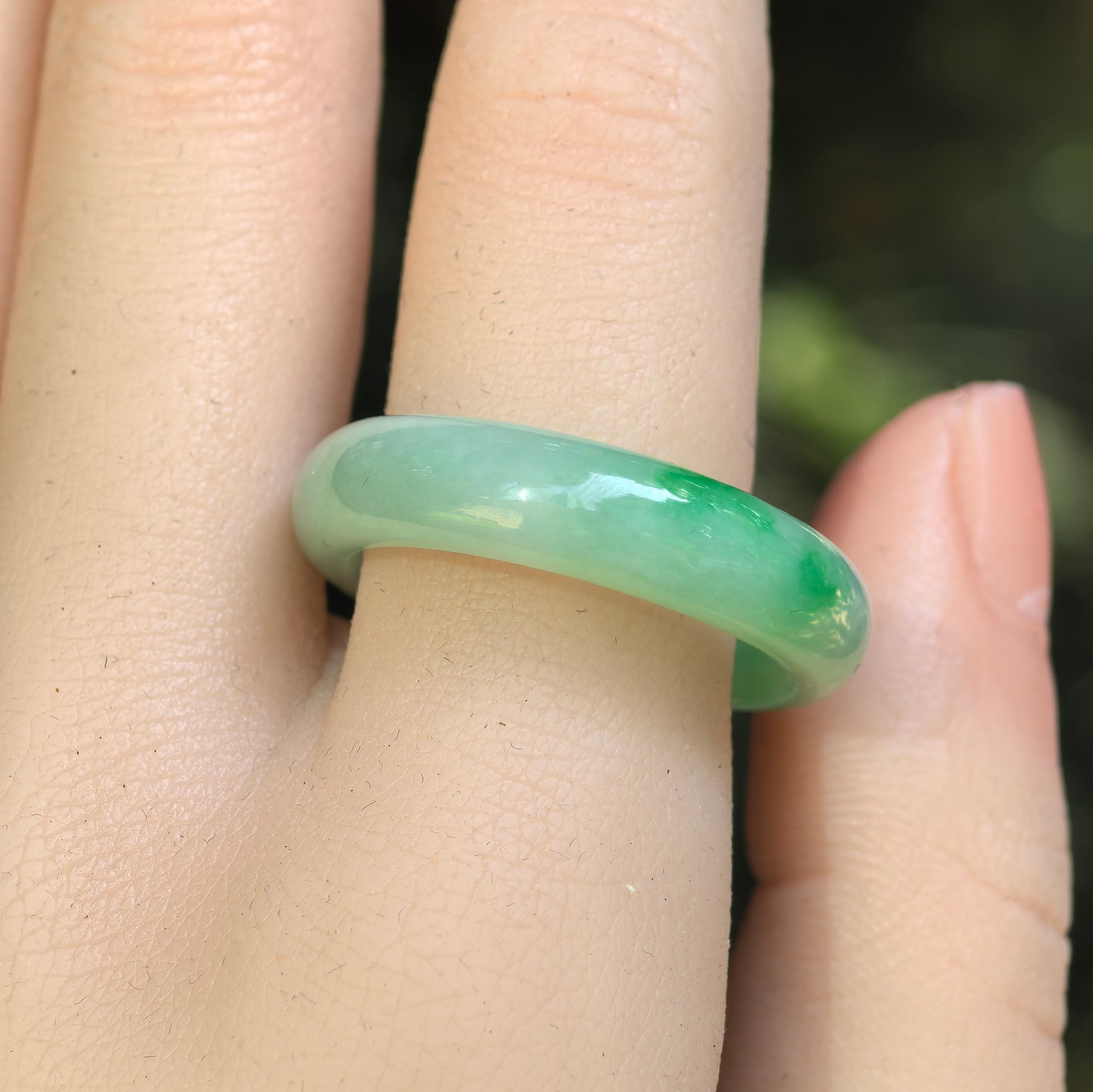 Close-up of light green jadeite ring band showing vivid green floating-flower accents.
