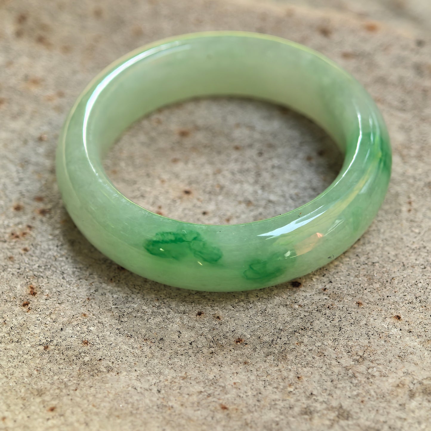 Side view of polished round jadeite ring band with smooth rounded profile.
