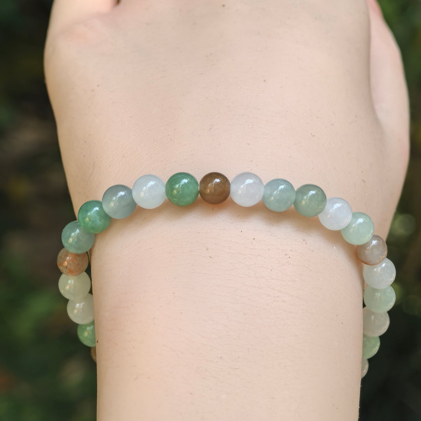 Close-up of 6 mm multicolor jadeite beads in light green, white, and brownish yellow tones.
