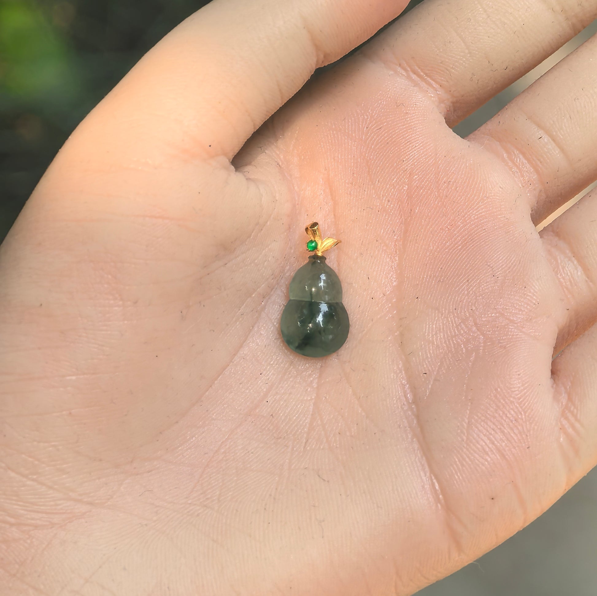 Petite carved gourd jadeite pendant with gold leaf bail and green accent stone.
