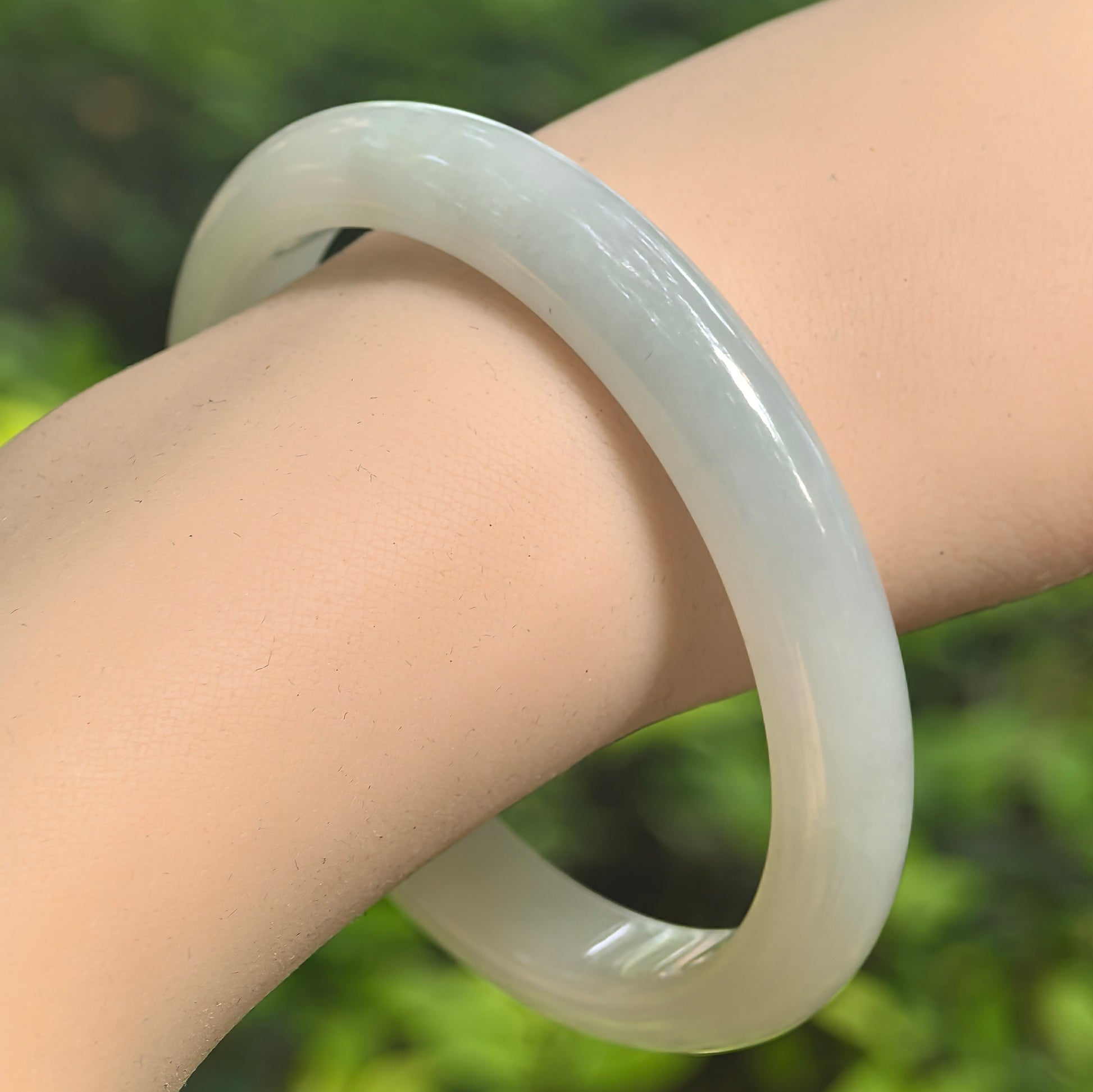 Natural Grade-A fine glutinous white-base light green jadeite bangle worn on the wrist.
