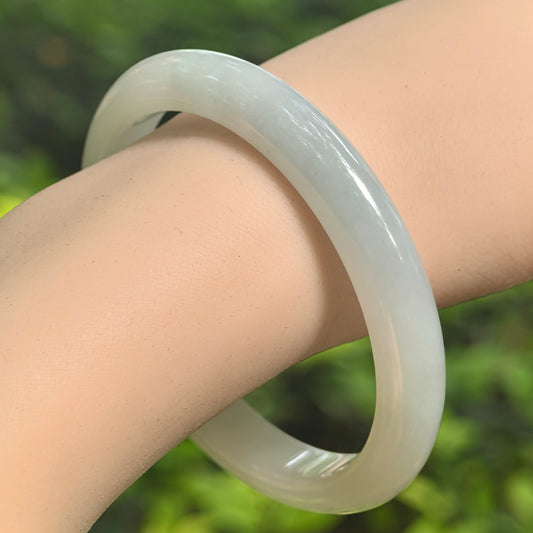 Natural Grade-A fine glutinous white-base light green jadeite bangle worn on the wrist.
