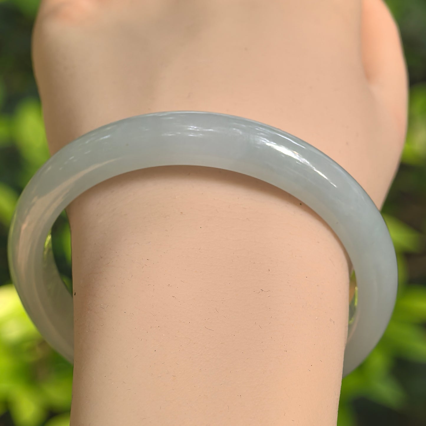 Close-up of light green jadeite bangle showing smooth polish and good translucency.

