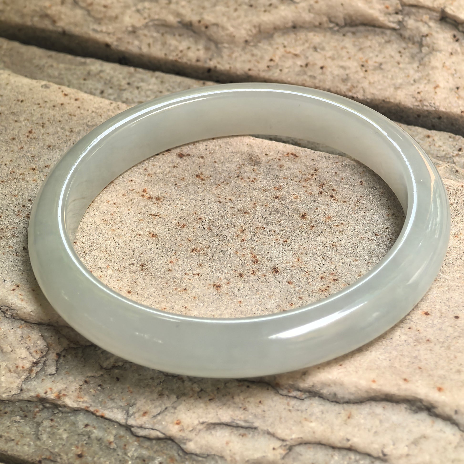 Fine glutinous light green jadeite bangle showing its round form and soft watery glow.
