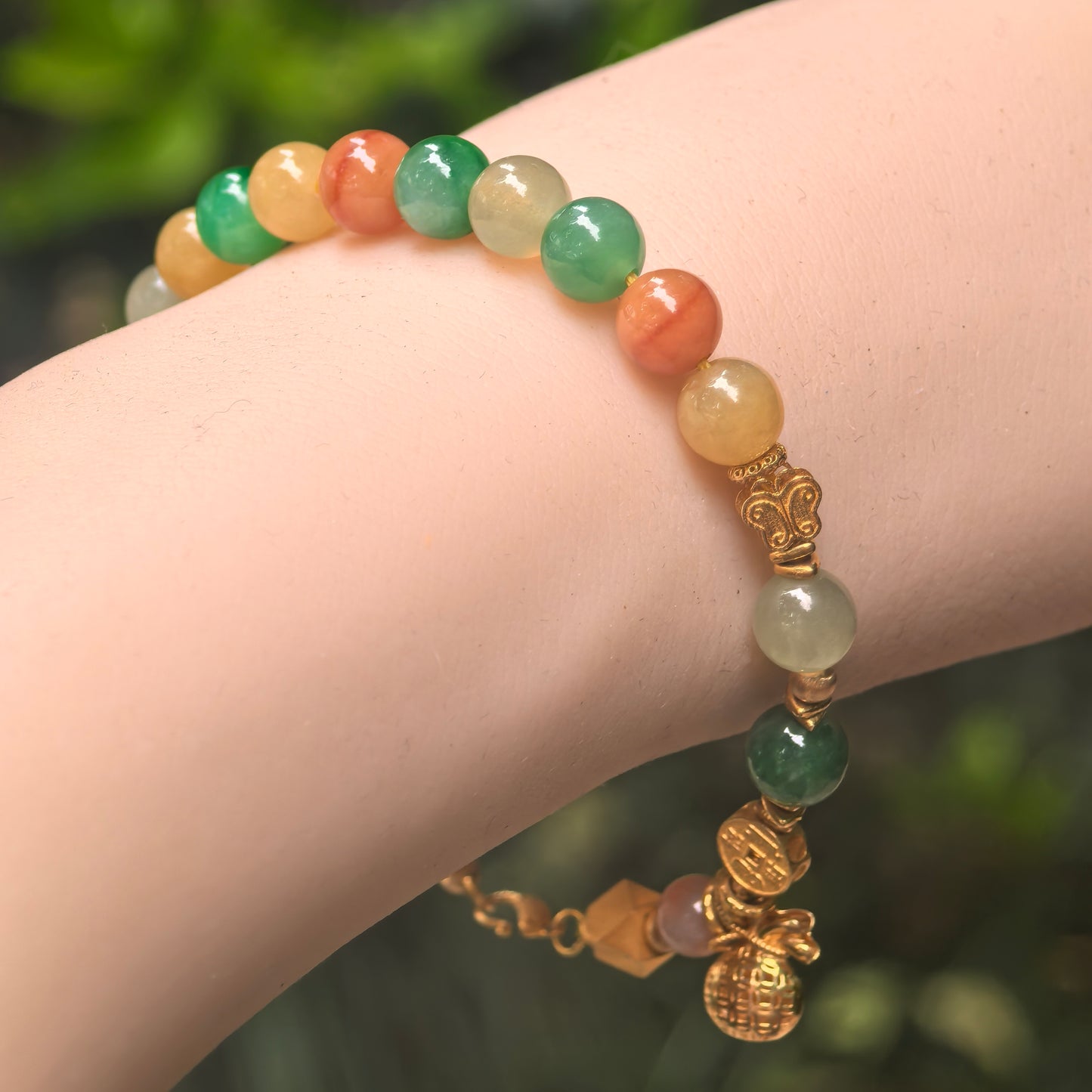 Natural Grade-A glutinous multicolor 18K gold jadeite bracelet worn on the wrist with colorful beads and gold accents.

