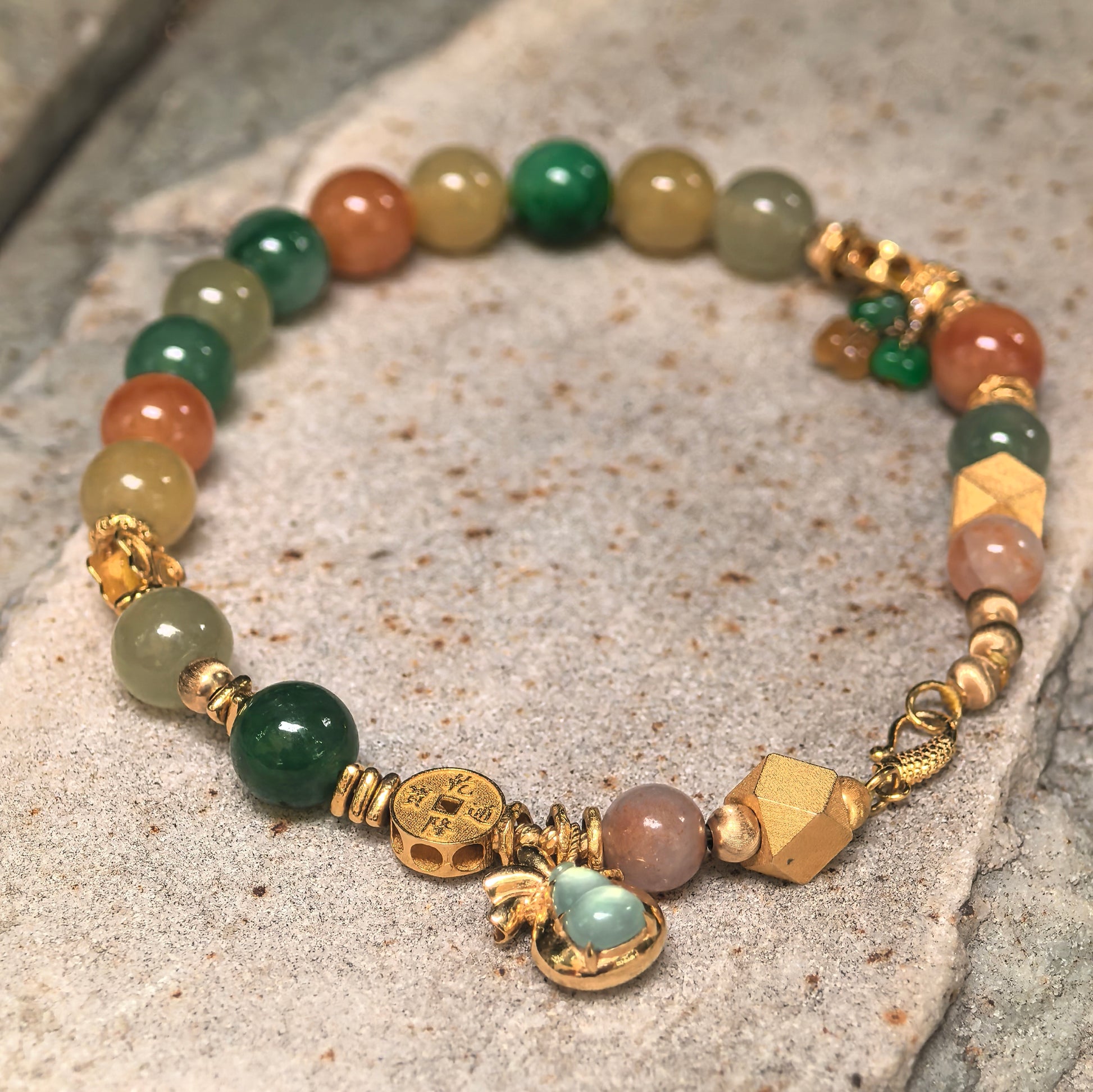 Close-up of glutinous multicolor jadeite bracelet with polished beads and 18K gold jewelry details.
