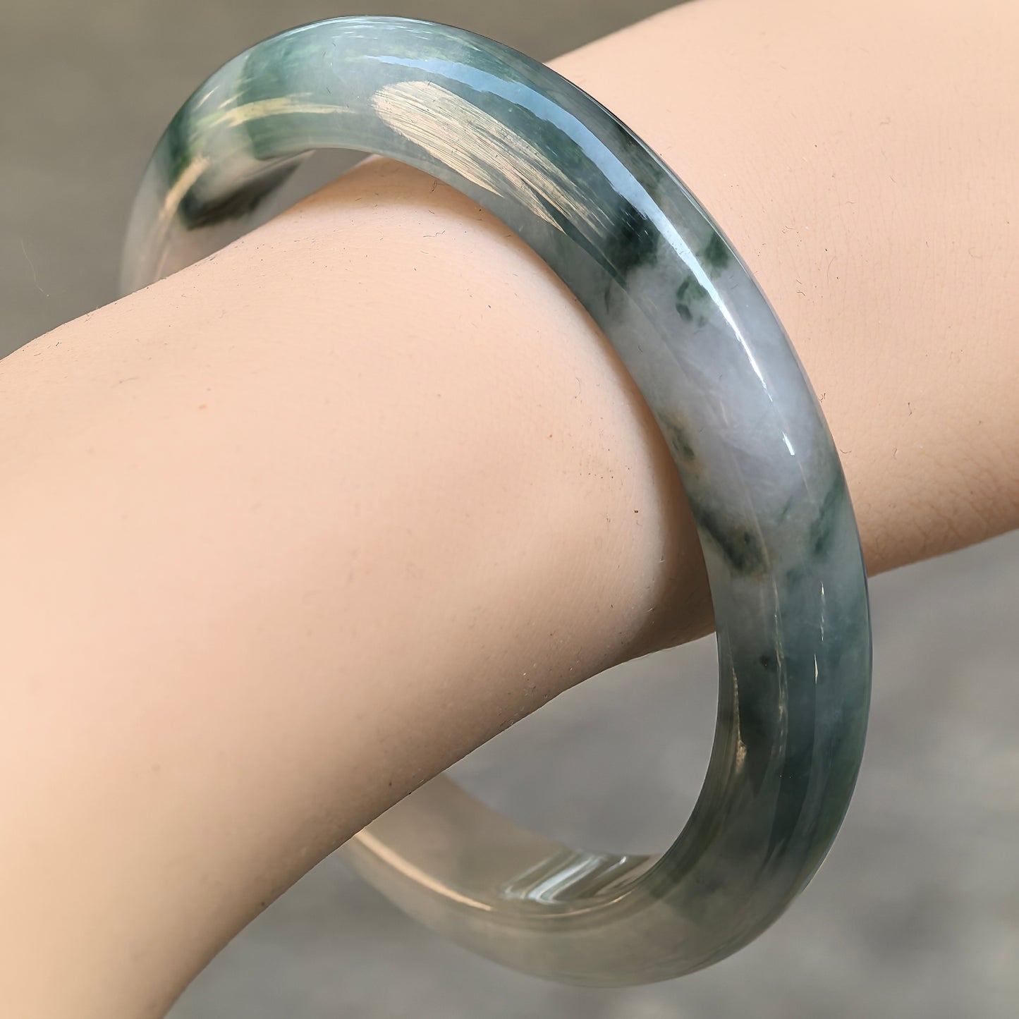 Natural Grade-A icy glutinous deep green floating flower jadeite bangle worn on the wrist.
